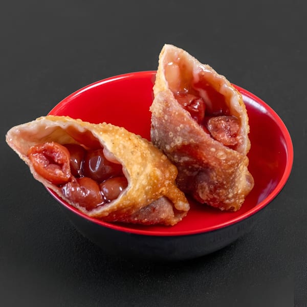 Two Blasian Fusion cherry dessert egg rolls in a red and black bowl.